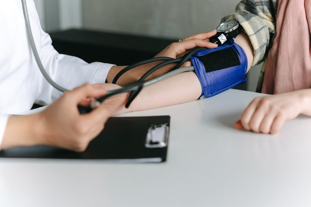 A healthcare worker uses a sphygmomanometer to check a patients blood pressure in a medical office.